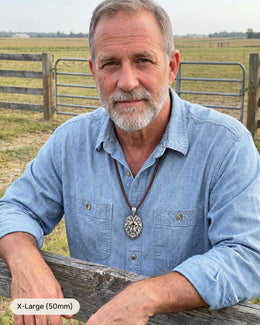 Man wearing the silver Cross & Lion, X-Large, on a leather necklace