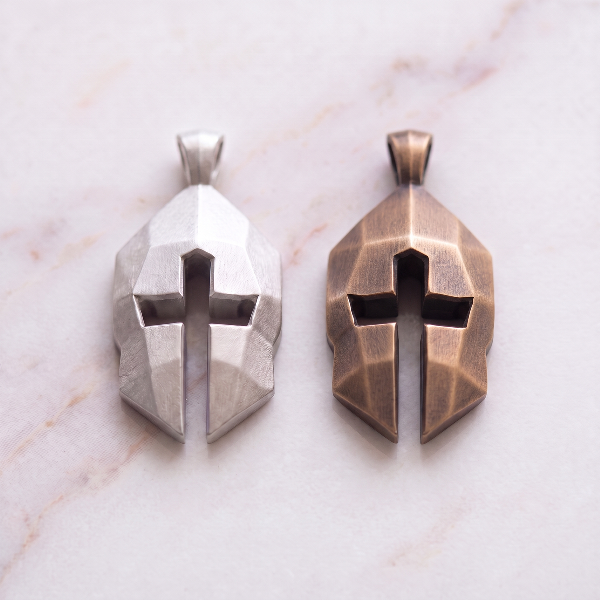 Women's Cross & Helm pendants in silver and bronze on white marble