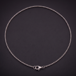 2 mm stainless steel box chain necklace laid in a loop on black, lobster clasp fastened