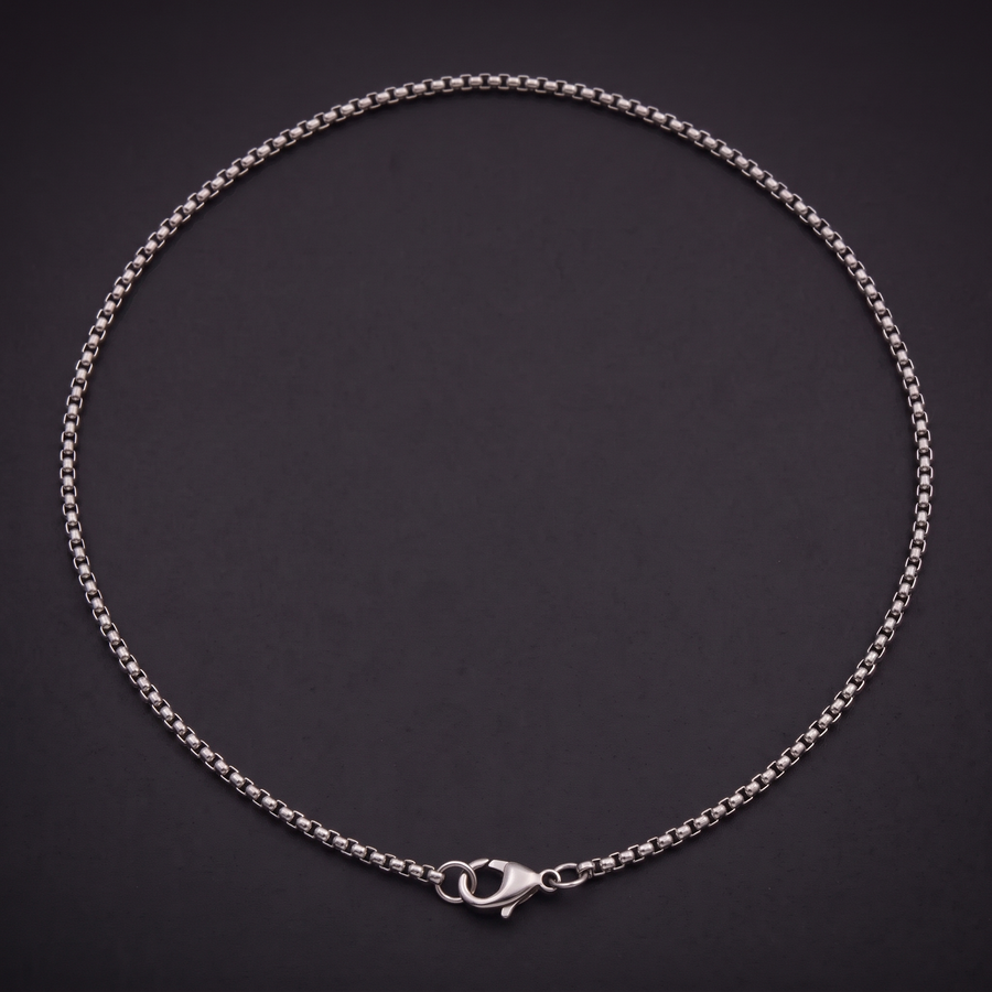 2 mm stainless steel box chain necklace laid in a loop on black, lobster clasp fastened