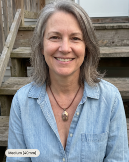 Woman wearing the bronze Women's Cross & Helm, Medium 40mm, on a brown leather necklace