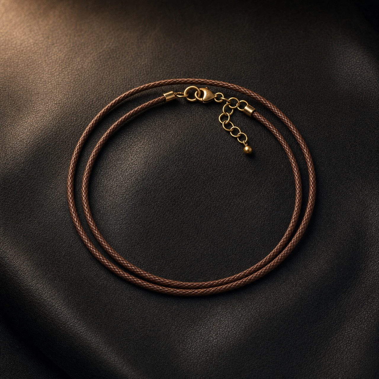 Brown leather necklace coiled on a dark surface