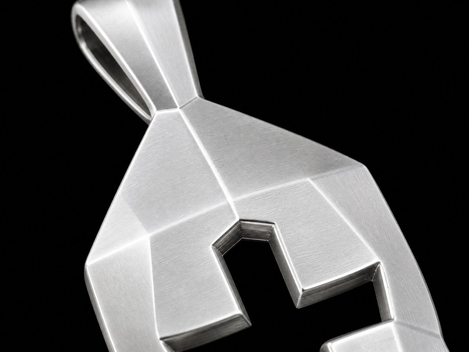 Extreme macro detail of a Cross and Helm pendant showing brushed texture cross cutout and beveled geometry